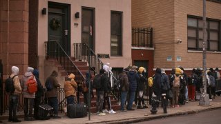 Migrants queue in the cold as they look for a shelter outside a migrant assistance center at St. Brigid Elementary School on Tuesday, Dec. 5, 2023, in New York. It could be a cold, grim New Year for thousands of migrant families living in New York City’s emergency shelter system. With winter setting in, they are being told they need to clear out, with no guarantee they’ll be given a bed elsewhere. (AP Photo/Andres Kudacki)