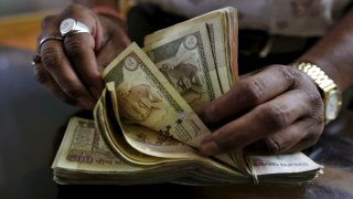 A money lender counts Indian rupee currency notes at his shop in Ahmedabad, India.