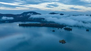 Aerial view above clouds of Blue Mountain Lake at sunrise in Adirondack, New York State.
