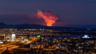 A volcano is spewing lava and smoke as it erupts in Reykjanes Peninsula, Iceland, on January 14, 2024. The volcanic eruption, which occurred in southwest Iceland on Sunday, presents an imminent danger to a neighboring fishing village, which had been previously evacuated due to concerns about a potential eruption, officials say.