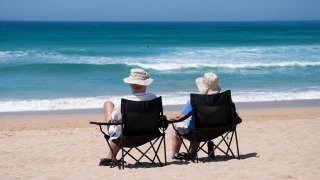Couple sitting on deck chairs by the sea
