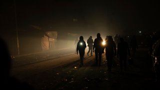 Palestinians displaced by the Israeli bombardment of the Gaza Strip walk in the dark with flashlights at the makeshift tent camp in the Muwasi area on Dec. 31, 2023.