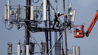 A worker climbs on a cellular communication tower in Oakland, California.
