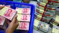 A bank employee count China’s renminbi (RMB) or yuan notes next to U.S. dollar notes at a Kasikornbank in Bangkok, Thailand, January 26, 2023.