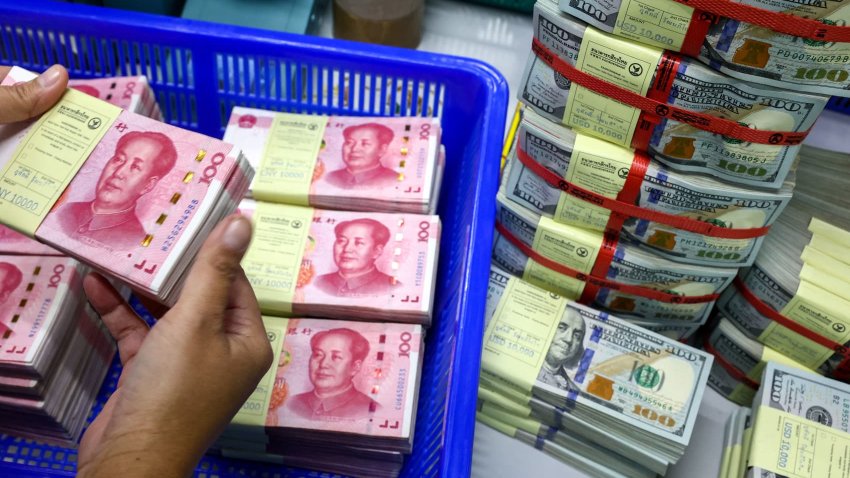 A bank employee count China’s renminbi (RMB) or yuan notes next to U.S. dollar notes at a Kasikornbank in Bangkok, Thailand, January 26, 2023.