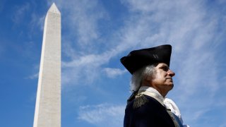 John Lopes, playing the part of President George Washington, stands near the Washington Monument