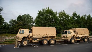 A US Army National Guard Soldier leans onto a high-water rescue truck as he waits for his fellow soldiers in a supermarket parking lot as they grab meals before the arrival of Hurricane Henri in East Lyme, New Londo, Connecticut on August 21, 2021. - A swath of the US East Coast, including New York City, was under alert Saturday, as storm Henri was upgraded to what could be the first hurricane in 30 years to hit New England. (Photo by JOSEPH PREZIOSO / AFP) (Photo by JOSEPH PREZIOSO/AFP via Getty Images)