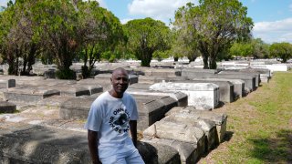 Jessie Wooden, owner of the Lincoln Memorial Park Cemetery, sits on a crypt on Feb. 26, 2024, in the Brownsville neighborhood of Miami.