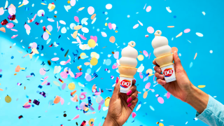 Two people holding Dairy Queen vanilla cones amid confetti flying in the air.