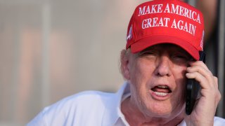 Republican presidential candidate, former President Donald Trump speaks on the phone as he watches play in the final round of LIV Golf Miami, at Trump National Doral Golf Club, Sunday, April 7, 2024, in Doral, Fla.