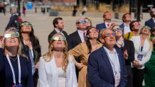 People gather to look on during a solar eclipse outside the Fiserv Forum Monday, April 8, 2024