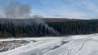 A fire burns after a Douglas C-54 Skymaster plane crashed into the Tanana River outside Fairbanks, Alaska.