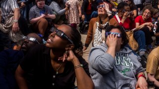 People watch the solar eclipse through special viewing glasses at the Franklin Institute