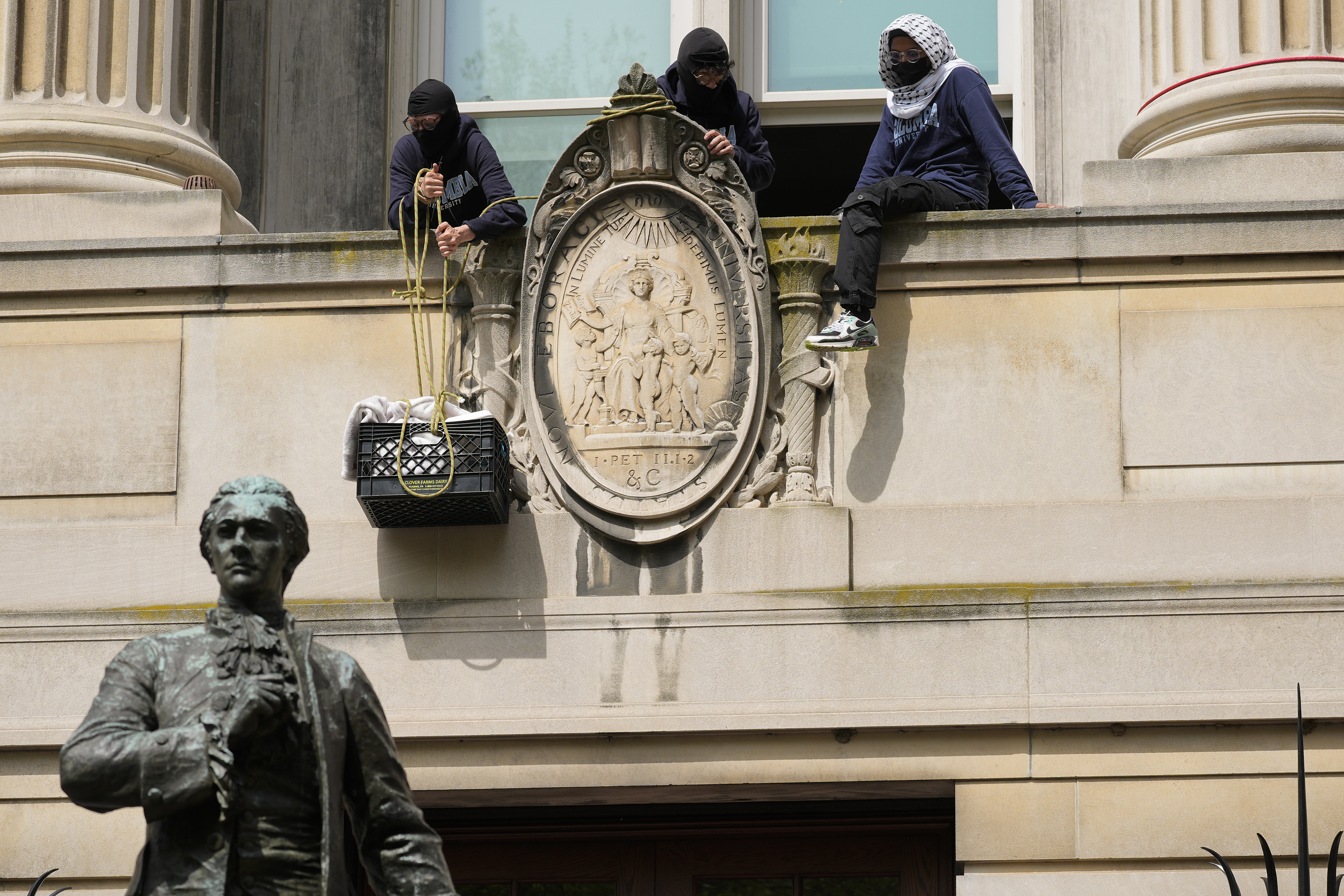 NEW YORK, NEW YORK – APRIL 30: A student protester pulls up a crate filled with foot and supplies from a balcony of Hamilton Hall on the campus of Columbia University on April 30, 2024 in New York City. All classes at Columbia University have been held virtually today after school President Minouche Shafik announced a shift to online learning in response to recent campus unrest. (Photo by Mary Altaffer-Pool/Getty Images)