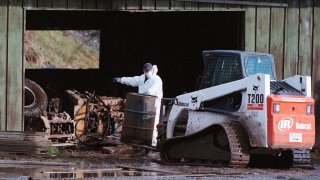 FILE - Royal Canadian Mounted Police investigators move debris on a pig farm