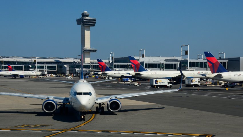 NEW YORK, NY – SEPTEMBER 24, 2017:  A Delta Airlines passenger jet taxis at John F. Kennedy International Airport in New York, New York, with the airport’s 32 story, 321-foot tall control tower in the background.