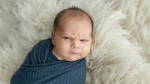 A baby making a face at the camera.