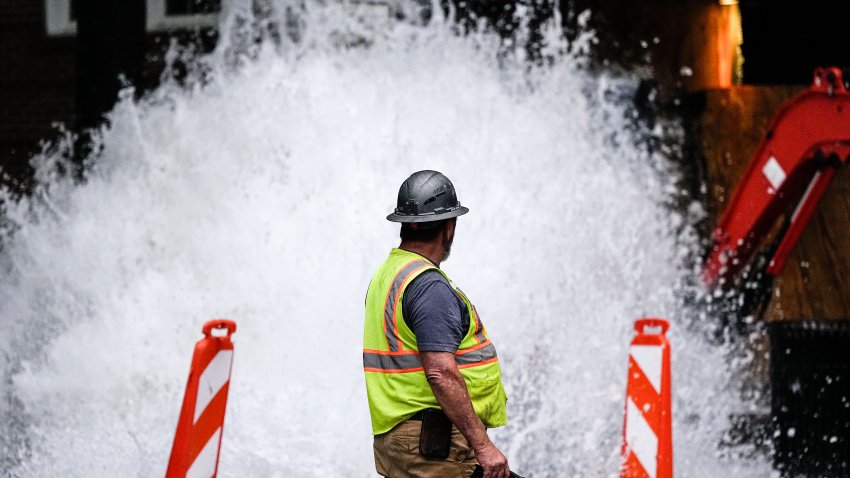 A crew member walks near a broken water transmission line