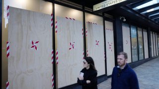 A couple walks past the boarded windows at the U.S. consulate as police investigate the vandalism in Sydney.