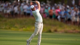 A person takes a swing at a golf tournament.