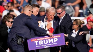 Republican presidential candidate former President Donald Trump is helped off the stage