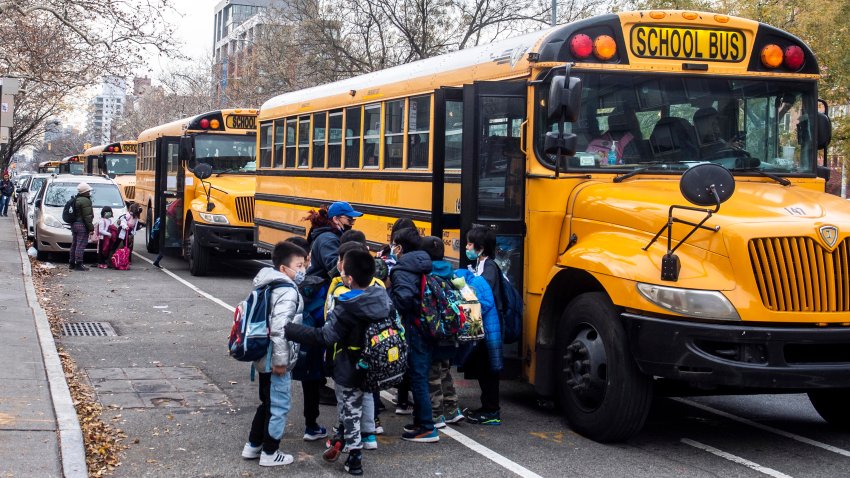 FILE — Students wearing masks board a school bus outside New Explorations into Science, Technology and Math school, in the Lower East Side neighborhood of New York, Dec. 21, 2021. In a reversal, New York Mayor Eric Adams is considering a remote option for schools.