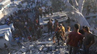 Palestinians search for bodies and survivors in the rubble of a residential building destroyed in an Israeli airstrike in Khan Younis, Gaza Strip, Wednesday, July 3, 2024.