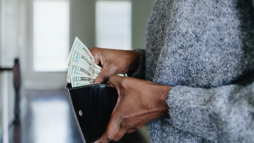 Close-up of unrecognizable black woman inserting twenty dollar bills into her wallet