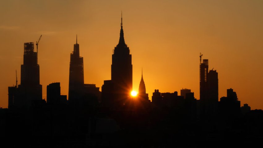 JERSEY CITY, NJ – JULY 16: The sun rises behind the Empire State Building and Chrysler Building in New York City as a heat wave continues on July 16, 2024, as seen from Jersey City, New Jersey.  (Photo by Gary Hershorn/Getty Images)