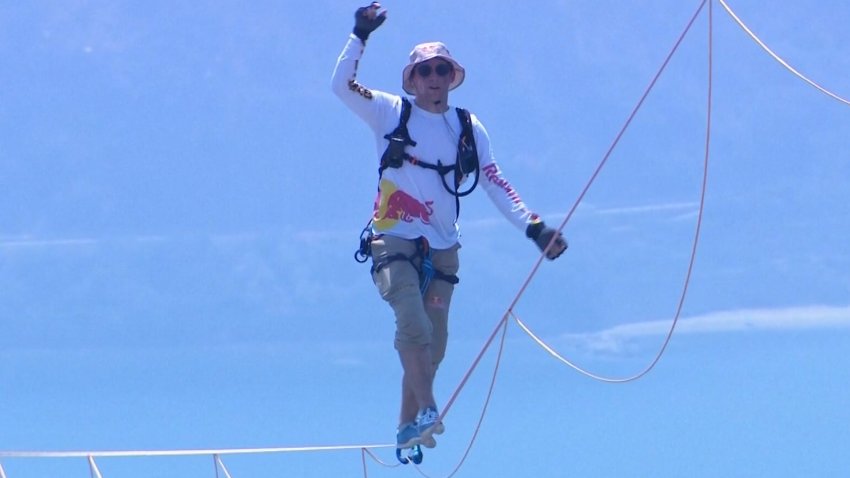 A close-up of a slackliner walking across a slack line hundreds of feet above the ocean.