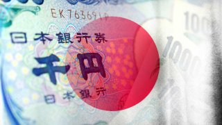 The Japan flag juxtaposed against a Japanese yen bank note.