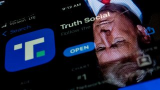 This photo illustration shows an image of former President Donald Trump reflected in a phone screen that is displaying the Truth Social app, in Washington, DC, on February 21, 2022.