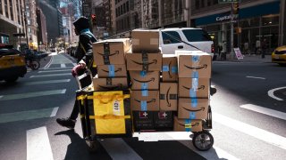 An Amazon contract worker pulls a cart of packages for delivery in New York, US, on Monday, April 22, 2024.