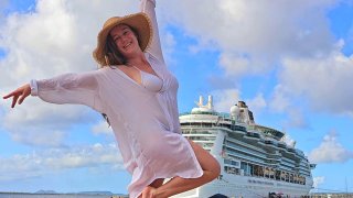 Jenny Hunnicutt poses in front of the Royal Caribbean Ultimate World Cruise, which she has been on for nearly nine months traveling the world. While on board, she is working remotely for her writing and consulting business based in Florida.