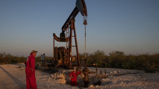 Hawk Dunlap, an oil well control specialist, and Sarah Stogner, an oil and gas lawyer, survey an excavated pumpjack with a leaking surface casing in Ward County, Texas, U.S., August 6, 2024.