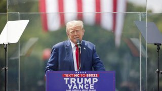 Republican presidential nominee and former U.S. President Donald Trump speaks from a bulletproof glass housing during a campaign rally, at the North Carolina Aviation Museum & Hall of Fame in Asheboro, North Carolina, U.S. August 21, 2024. 