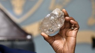 Botswana’s President Mokgweetsi Masisi holds a large diamond discovered in Botswana at his office in Gaborone on August 22, 2024.