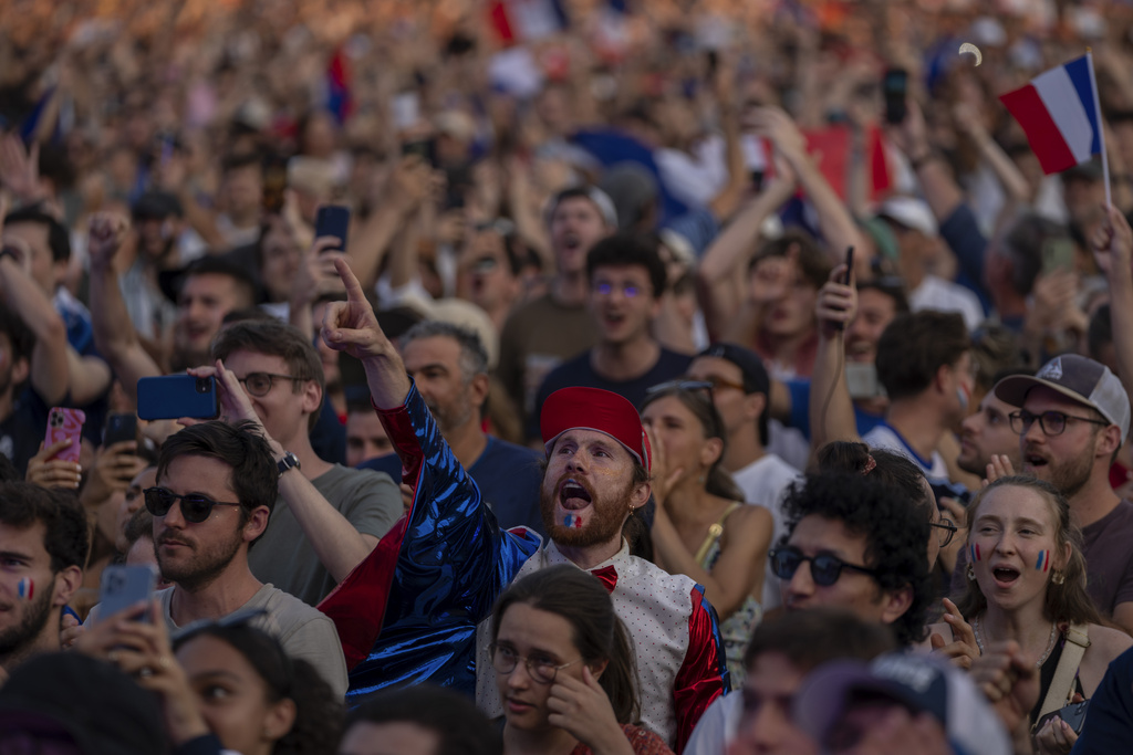 Spectators celebrate as they watch from a fan zone set up at the Club France, as Leon Marchand, of France, participates in men's 200-meter individual medley final, at the 2024 Summer Olympics, Friday, Aug. 2, 2024, in Paris, France. (AP Photo/Dar Yasin)