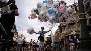 A bundle of balloons is held by an employee as guests walk through Disney World’s Magic Kingdom on Saturday, June 3, 2023 in Lake Buena Vista, Fla.