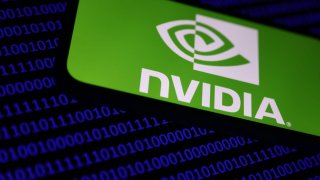 A binary code is displayed on a laptop screen in the background, while the Nvidia logo is showcased on a phone on April 28, 2024. 