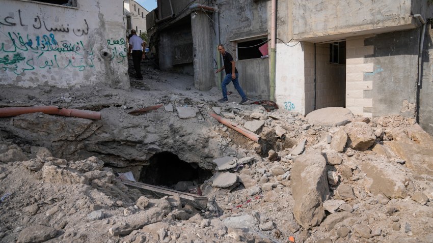 Palestinians walk past a damaged building following an Israeli military operation in the West Bank city of Jenin on Friday, Sept. 6, 2024.