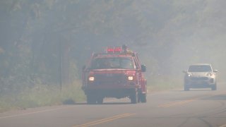 A firefighting vehicle drives along a smoke-filled road in Berkeley Township N.J. on the edge of a forest fire on Tuesday, Sept. 10, 2024. (AP Photo/Wayne Parry)