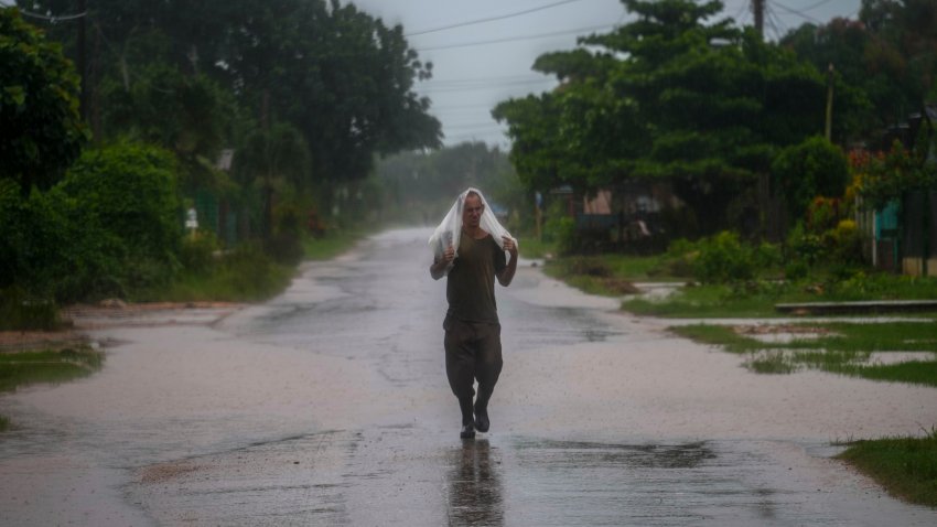 A resident uses a piece of plastic as protection from heavy rains brought on by Hurricane Helene, in Batabano, Cuba, Wednesday, Sept. 25, 2024.