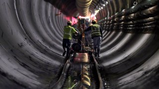 FILE – Tunnel workers push equipment up a rail track to a machine boring a 2.5-mile bypass tunnel for the Delaware Aqueduct in Marlboro, N.Y., May 16, 2018.