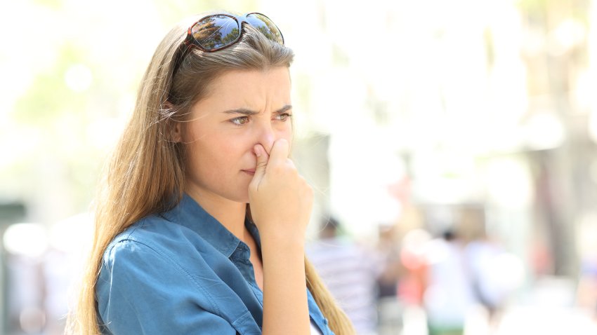 Girl covering her nose due to bad odour in the street