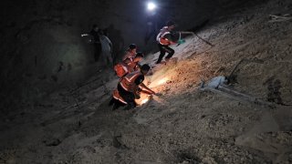 Teams search for people under sand during a rescue operation after Israeli airstrike on a tent encampment of displaced Palestinians