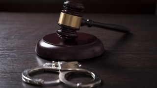 Gavel and handcuffs on top of a table in a courtroom