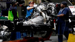 Line workers work on the chassis of full-size General Motors pickup trucks at the Flint Assembly plant on June 12, 2019 in Flint, Michigan.