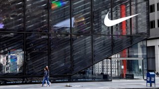 People wearing protective face masks walk past the closed Nike store on 5th Avenue during the outbreak of Covid-19, in New York City on May 11, 2020.