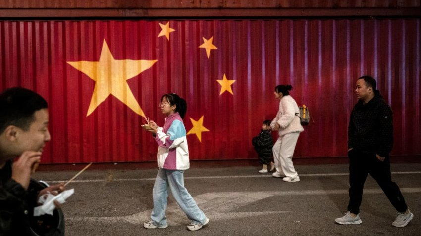 Visitors walk by a large Chinese national flag painted on the side of a container at an outdoor market during the Golden Week holiday on October 3, 2024 in Beijing, China. China marked its National Day and the 75th anniversary of the founding of the Peoples Republic on October 1st. 